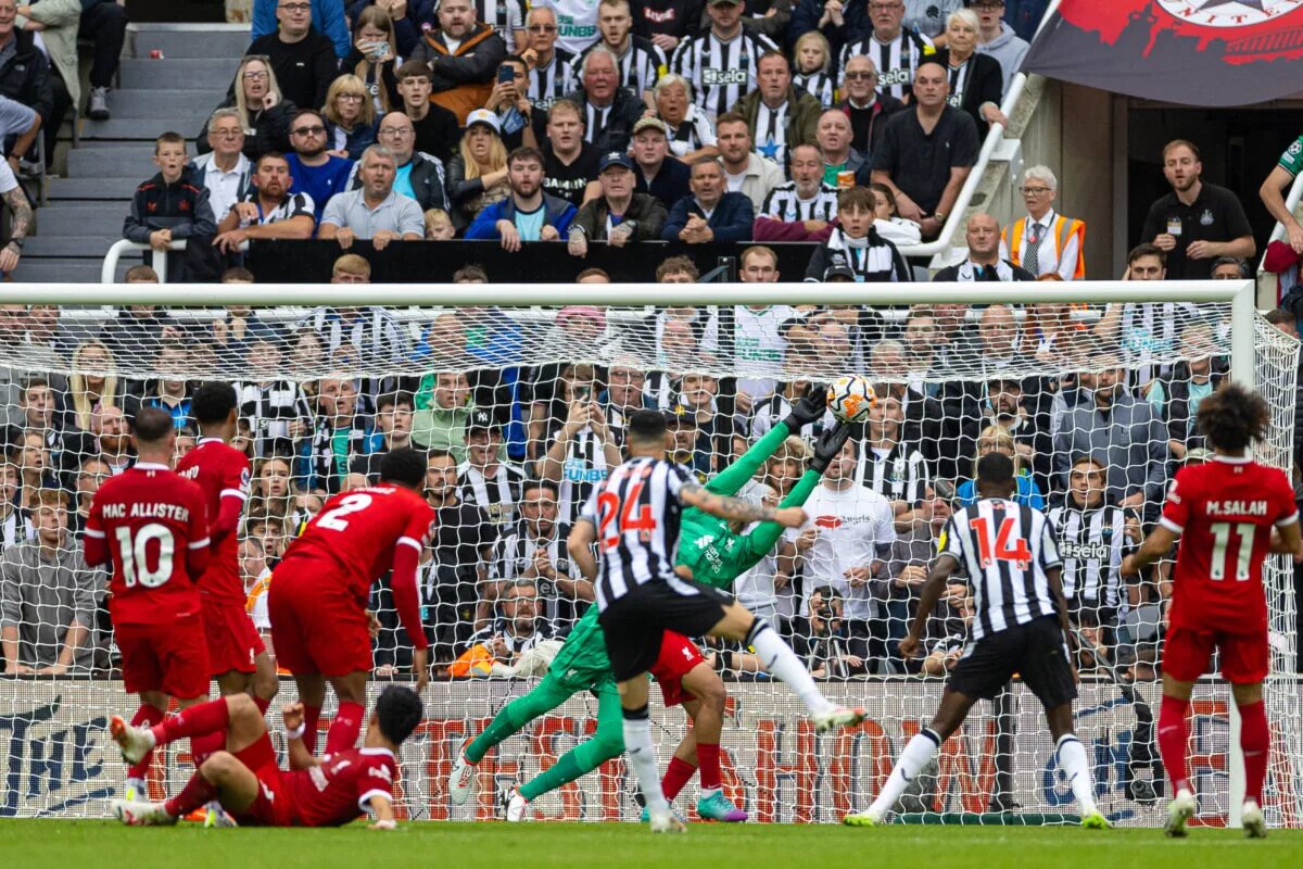 Liverpool and newcastle players watch on as a shot heads towards goal