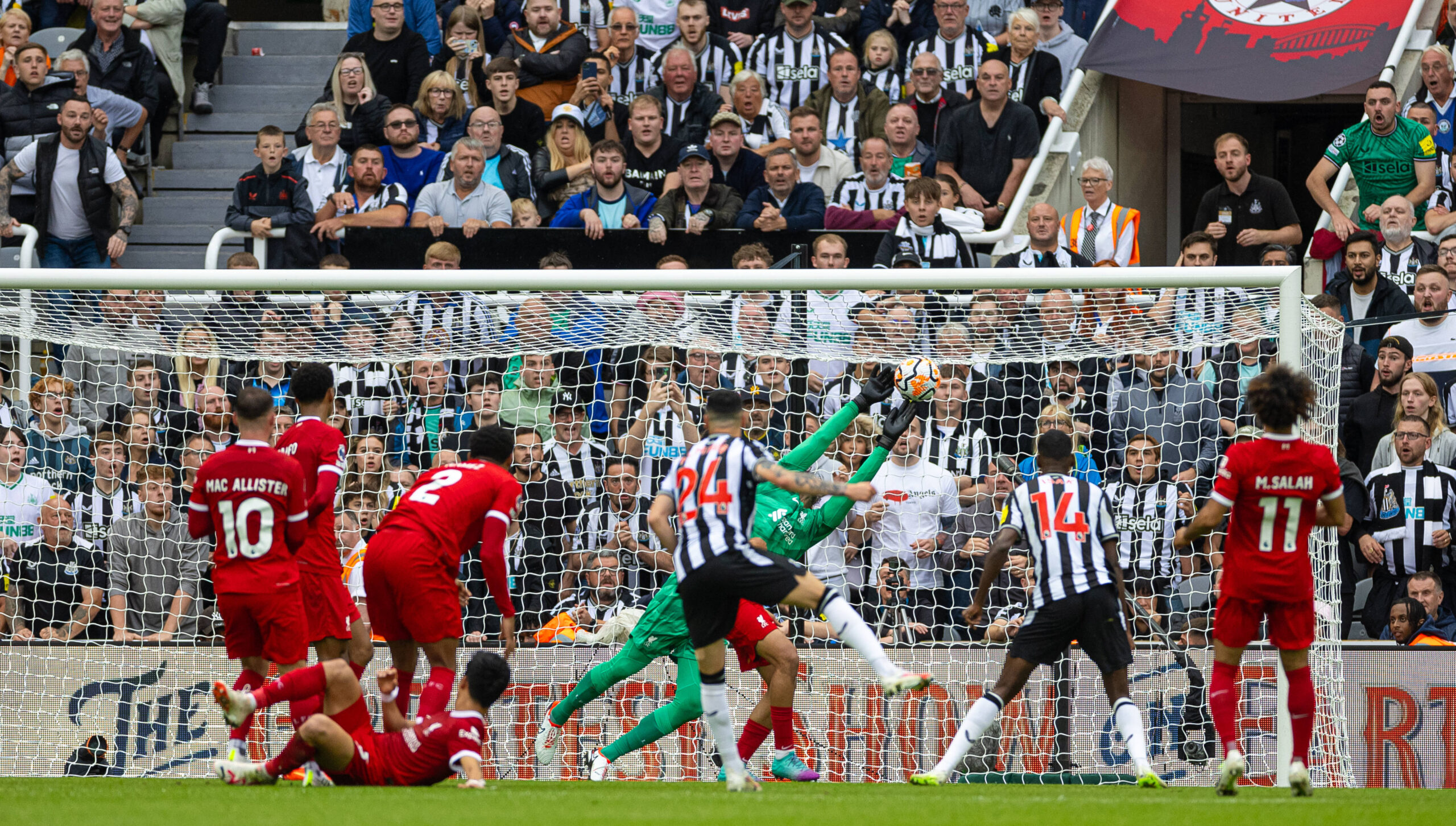 Liverpool and newcastle players watch on as a shot heads towards goal