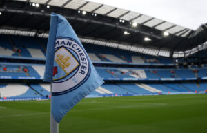 Image of an empty Etihad stadium focusing on a corner flag bearing Manchester City crest
