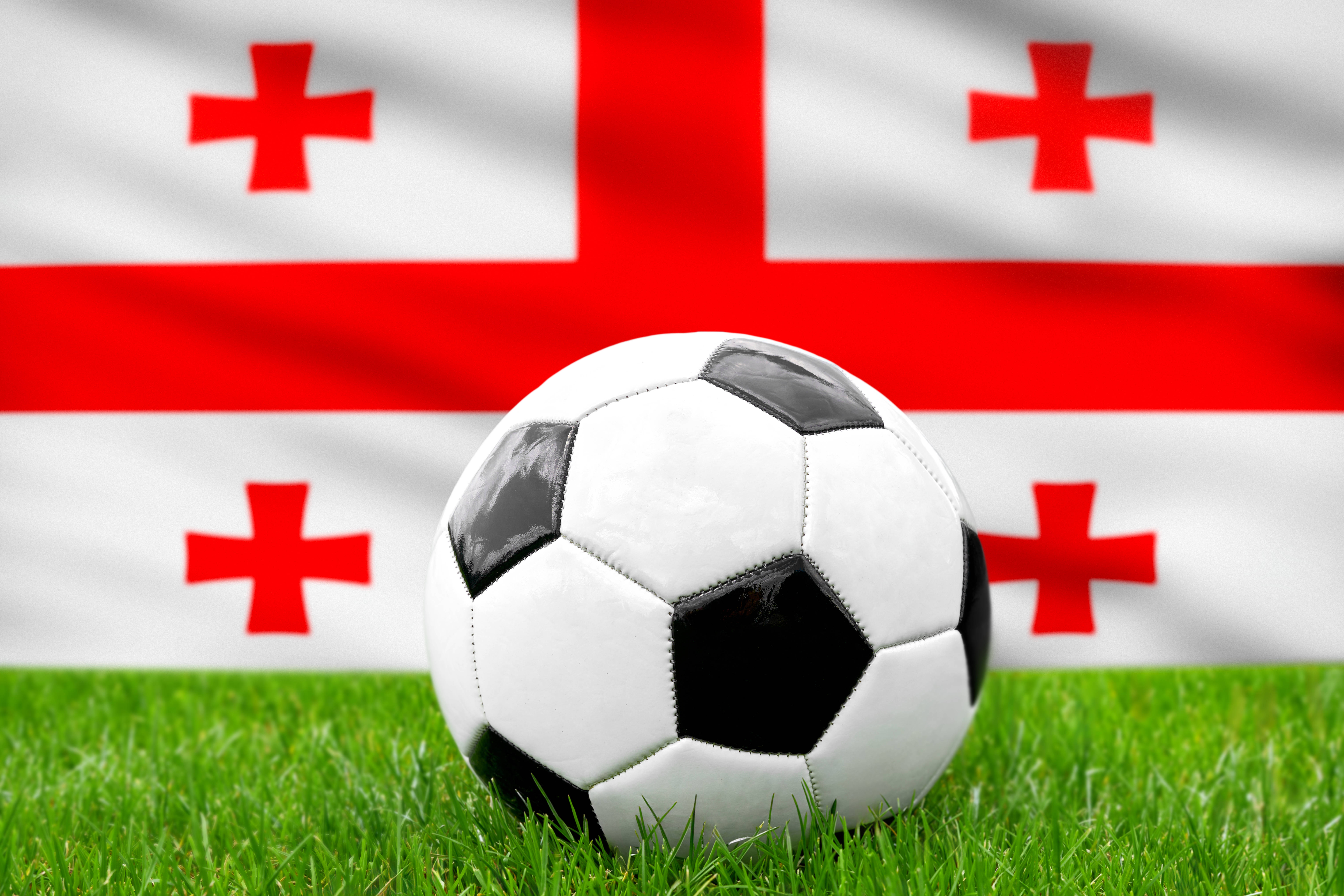 Image of the Georgian flag with a football in front of it