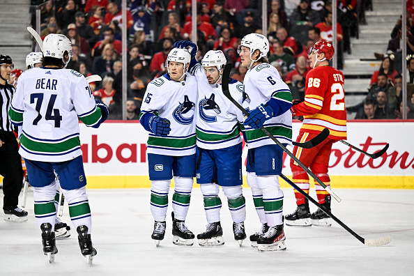 CALGARY, AB - DECEMBER 31: Vancouver Canucks Center Sheldon Dries (15) celebrates a goal with Vancouver Canucks Left Wing Conor Garland (8), Vancouver Canucks Defenceman Ethan Bear (74) and Vancouver Canucks Right Wing Brock Boeser (6) during the second period of an NHL game between the Calgary Flames and the Vancouver Canucks on December 31, 2022, at the Scotiabank Saddledome in Calgary, AB. (Photo by Brett Holmes/Icon Sportswire via Getty Images)