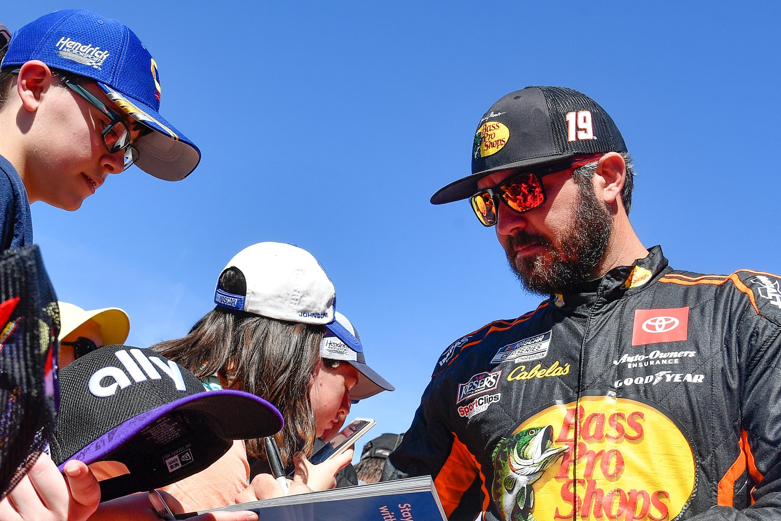 AVONDALE, ARIZONA - MARCH 13: Martin Truex Jr., driver of the #19 Bass Pro Shops Toyota, signs autographs for fans during the red carpet prior to the Ruoff Mortgage 500 during at Phoenix Raceway on March 13, 2022 in Avondale, Arizona. (Photo by Logan Riely/Getty Images)