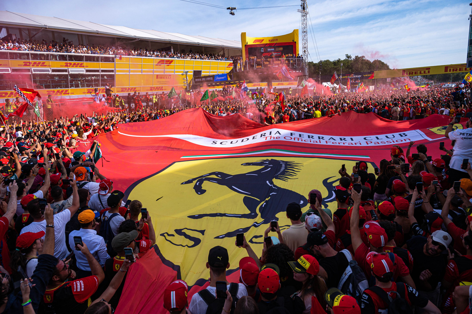 The podium of the Italian Grand Prix. Tifosi enrolling a giant Ferrari banner.