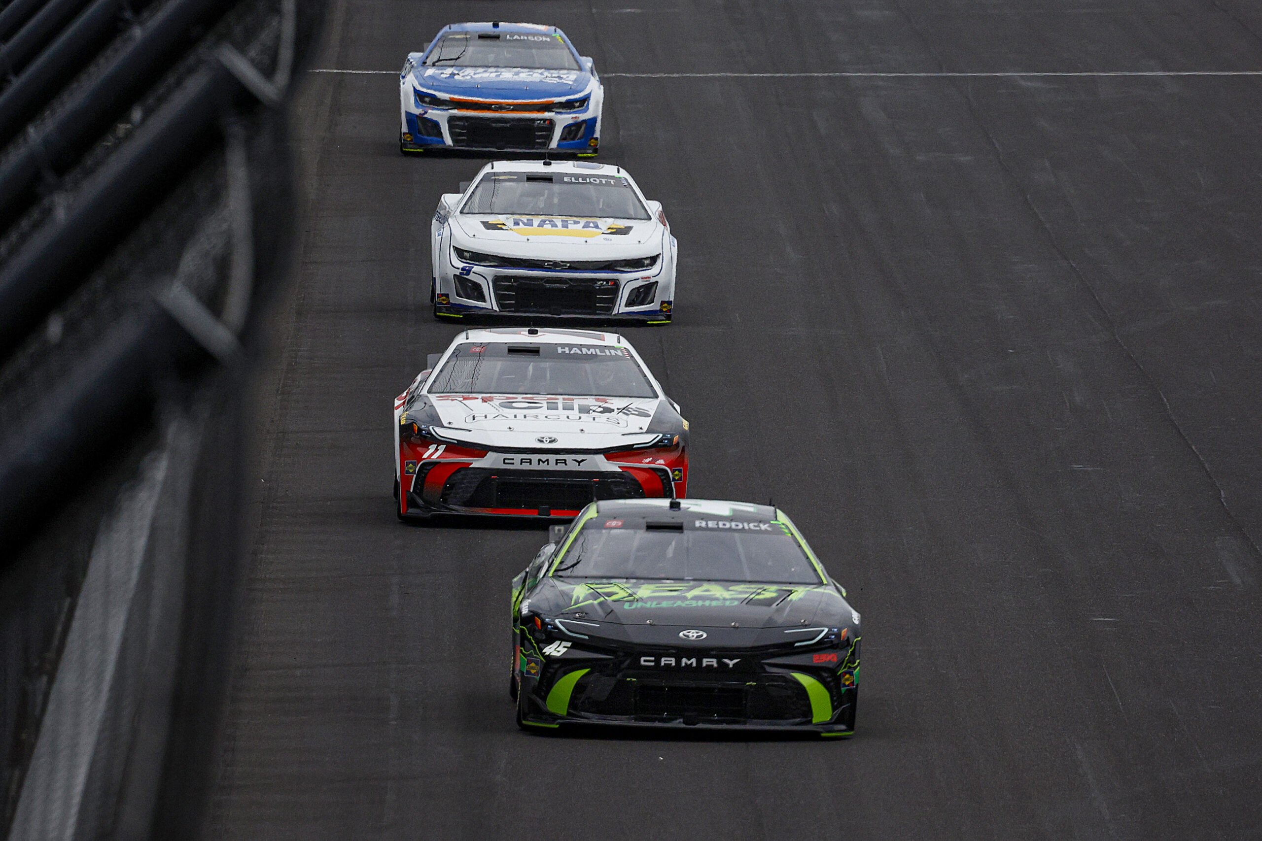 INDIANAPOLIS, INDIANA - JULY 21: Tyler Reddick, driver of the #45 The Beast Unleashed Toyota, Denny Hamlin, driver of the #11 Sport Clips Haircuts Toyota, Chase Elliott, driver of the #9 NAPA Auto Parts Chevrolet, and Kyle Larson, driver of the #5 HendrickCars.com Chevrolet, race during the NASCAR Cup Series Brickyard 400 at Indianapolis Motor Speedway on July 21, 2024 in Indianapolis, Indiana. (Photo by Sean Gardner/Getty Images)