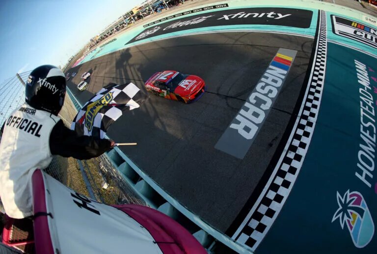 HOMESTEAD, FLORIDA - MARCH 22: Justin Allgaier, driver of the #7 BRANDT/TradeMark Nitrogen Chevrolet, takes the checkered flag to win the NASCAR Xfinity Series Hard Rock Bet 300 at Homestead-Miami Speedway on March 22, 2025 in Homestead, Florida. (Photo by Chris Graythen/Getty Images)