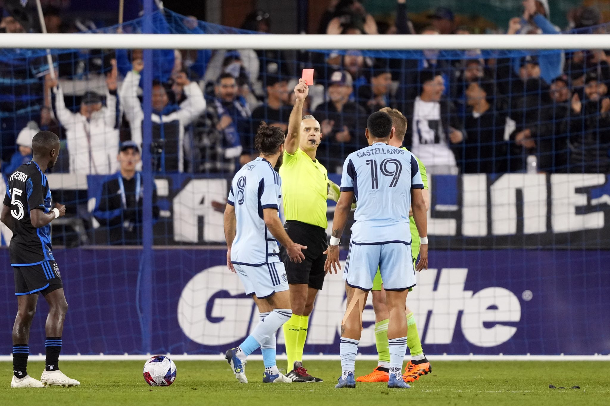  A soccer referee shows a red card to a player while other players look on during a game where England is struggling to retain possession.